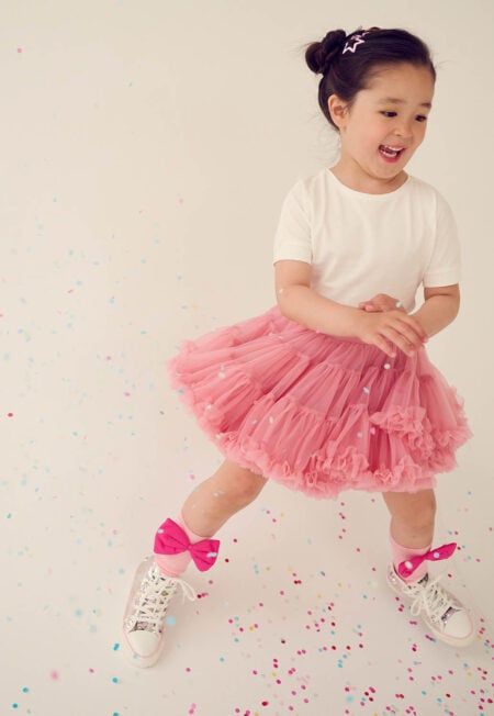 Bambina in gonna di tulle rosa intenso, calze al ginocchio rosa con fiocco rosa e maglietta basic bianca per bambina. Taglie disponibili: 80/86, 92/98, 98/104, 110/116, 122/128, 134, 140, 150