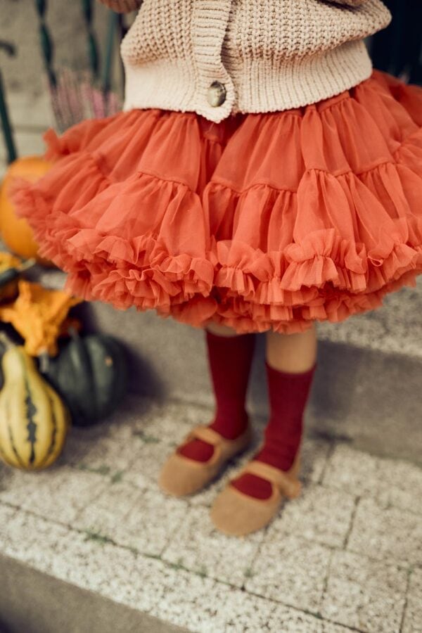 Falda de tul naranja para niñas con capas rizadas, combinada con calcetas y calcetas rojas. Tallas disponibles: 98/104, 110/116, 122/128, 134, 86/92