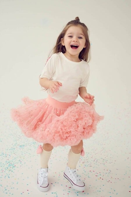 Bambina in gonna di tulle rosa con stelline, maglietta bianca con alucce rosa e calze beige al ginocchio con cuoricino. Taglie disponibili: 80/86, 92/98, 98/104, 110/116, 122/128, 134