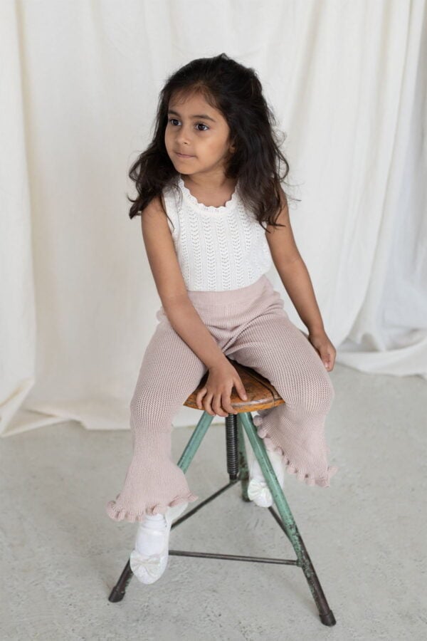 Conjunto de blusa sin mangas blanca y pantalones de campana rosa claro para niñas, con detalles en el dobladillo.