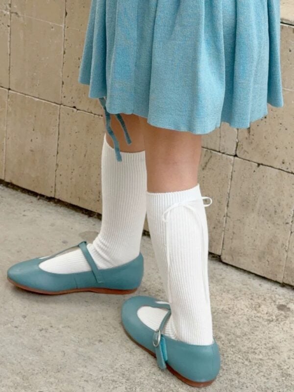 White knee-high socks for a girl with a thin bow and delicate ribbing.