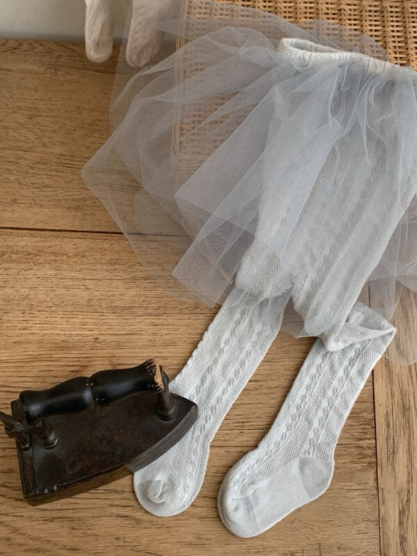 Grey tulle dress for a girl, white tights with decorative weave.