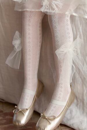 Openwork tights in off-white with a tulle bow, matching gold ballet flats. For a girl.