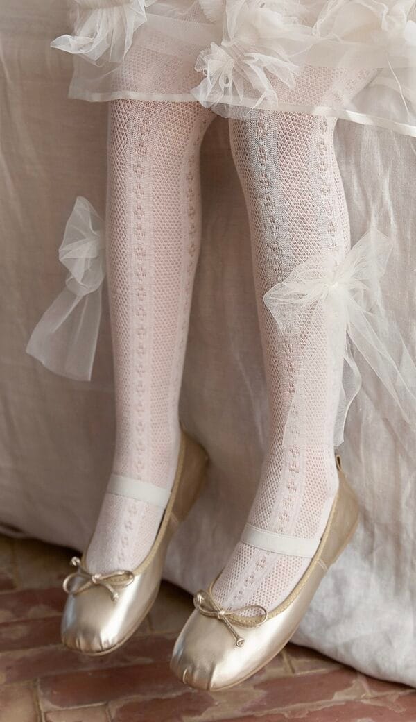 Openwork tights in off-white with a tulle bow, matching gold ballet flats. For a girl.
