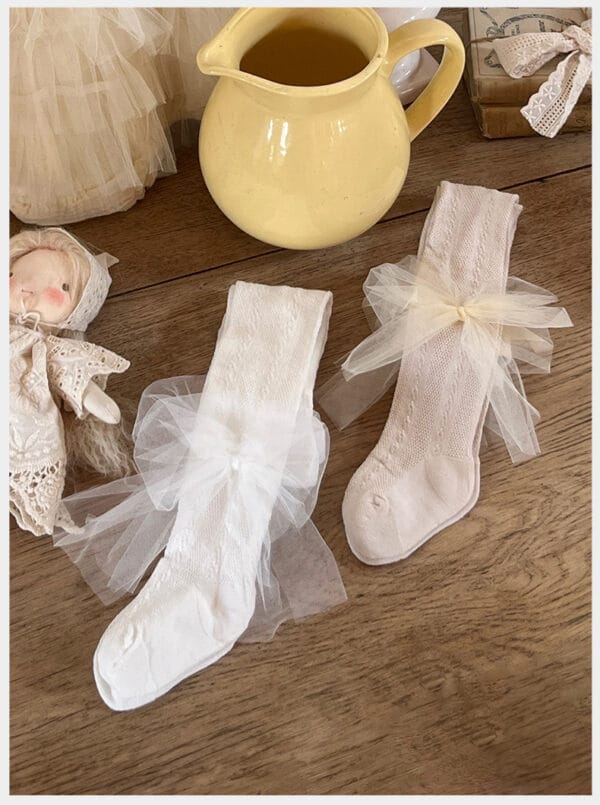White and pink socks for a girl with tulle bows on a wooden surface
