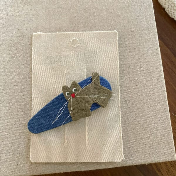 Hairpin for a girl in blue color with an embroidered cat in shades of olive-gray.