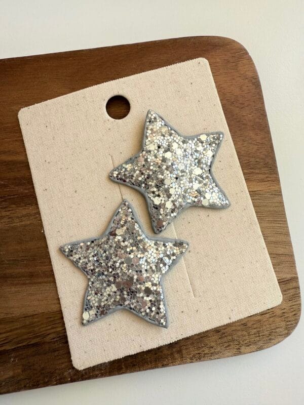 Silver hair clips in the shape of stars, covered with glitter, for a girl.