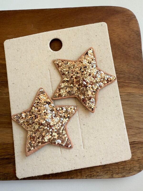 Gold star-shaped glitter hair clips for a girl.