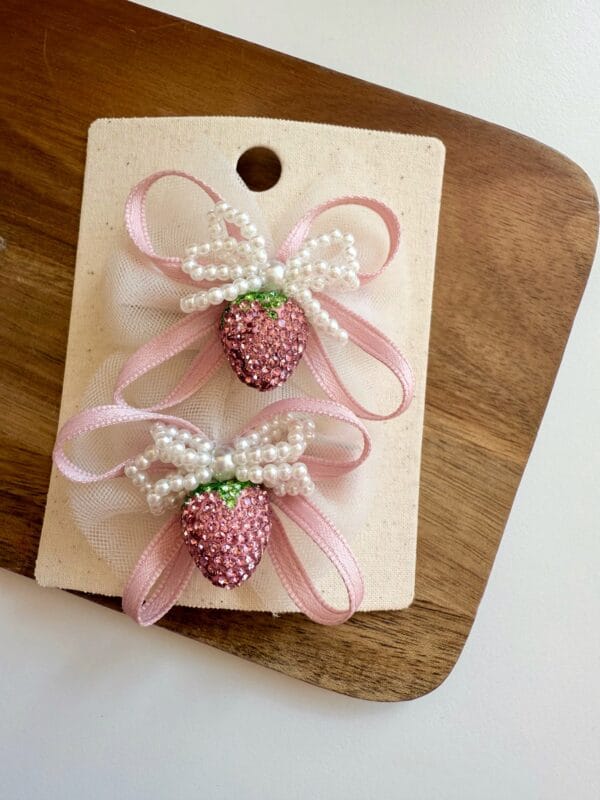 A set of pins for a girl with a pink bow and a sparkling strawberry. Decorated with pearls.