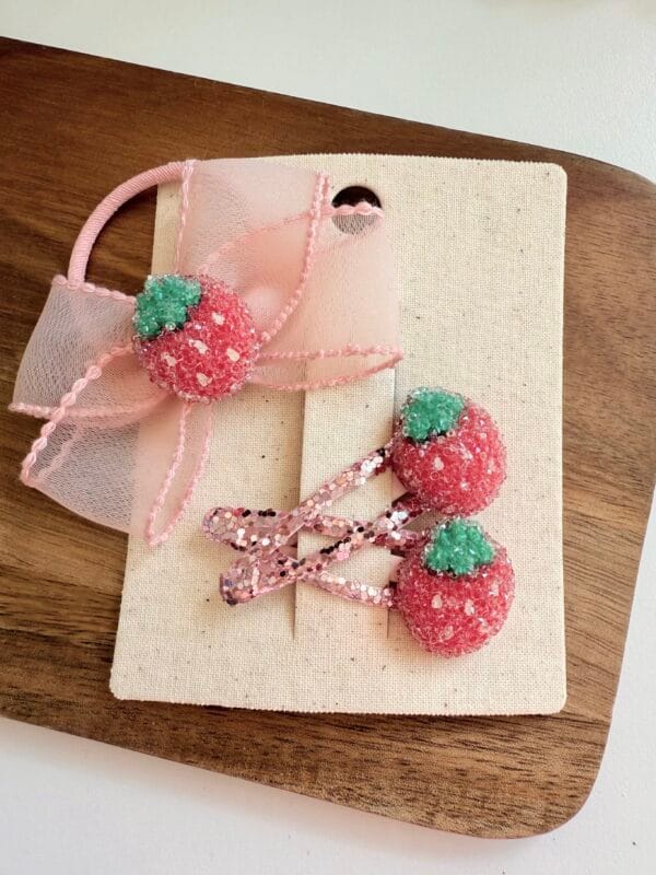 Pink colored bow ties with decorations in the shape of strawberries for girls, ideal for hair styling.