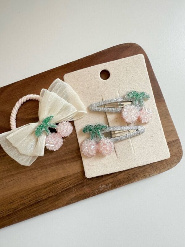Eraser and hair clips for girls in the shape of pink cherries with green leaves.