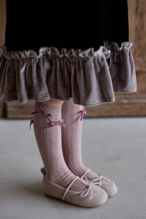Leather ballerinas for a girl in beige color, with pink tights and a frilly skirt.