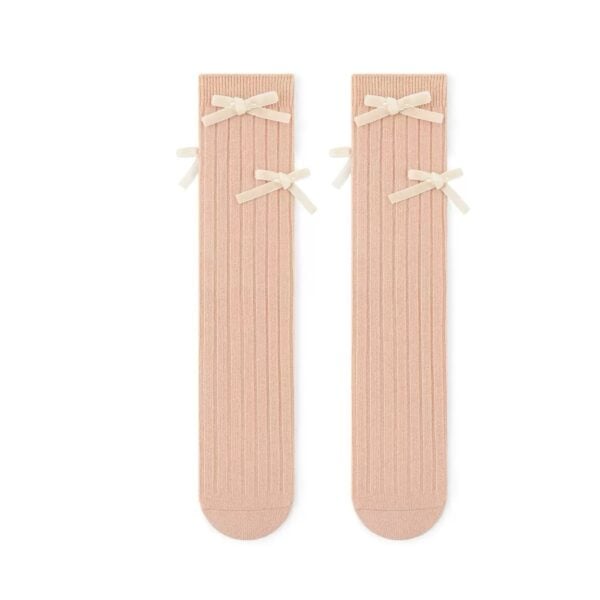 Knee-length socks in peach color with velvet bows for a girl.