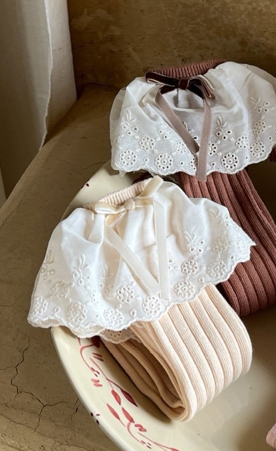 Vêtement de nuit blanc pour bébé fille avec broderie et collants roses et marrons.