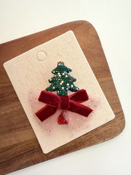 Green bow with a glittery Christmas tree for a girl on a light background.