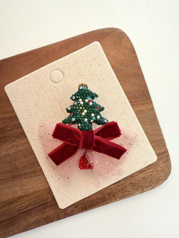 Green bow with a glittery Christmas tree for a girl on a light background.