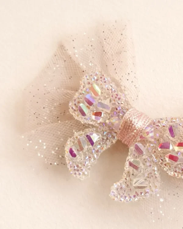 Glittery tulle hair clip featuring a shiny bow design, adorned with shimmering embellishments.
