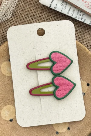 Heart-shaped hair clips, pink with green trim, for a girl.