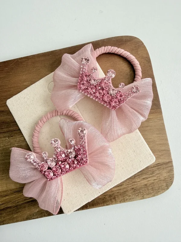 Hair ribbons for a girl in a pink shade with lace and crown-shaped embellishments.