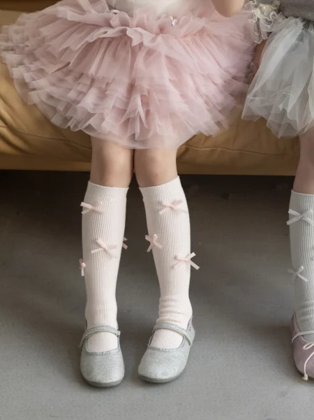 Gonna rosa in tulle per bambina, con calzini bianchi con fiocchi e scarpe lucide.