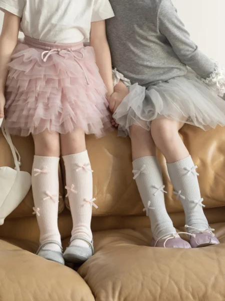 Calzini al ginocchio grigio chiaro con fiocchi per bambina, in materiale morbido, comodi da indossare.