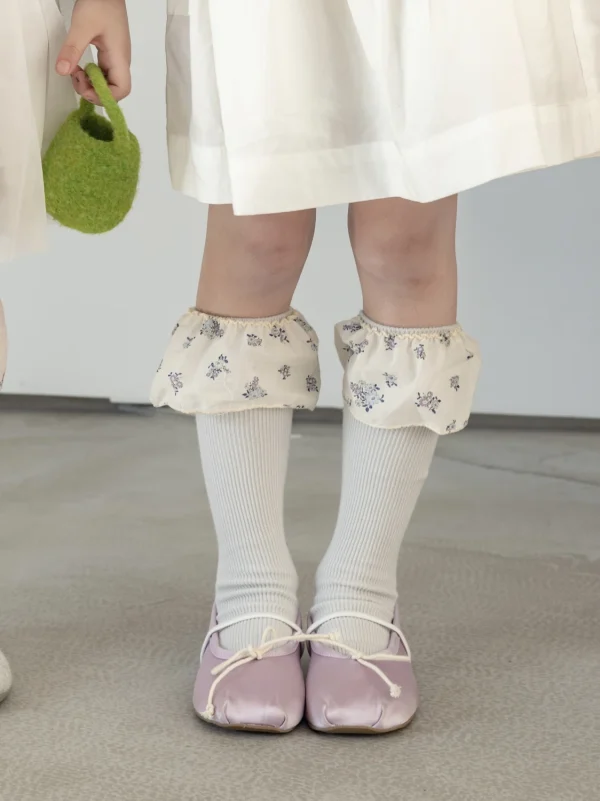 Pink ballet flats for a girl, white socks and embroidered white cuffs.