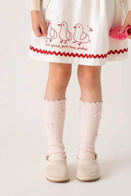 Calzini a coste rosa chiaro da bambina con fiocchi.
