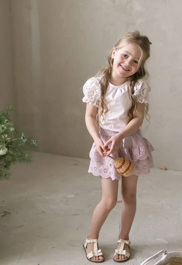 Pink blouse and skirt for a girl, decorated with lace details.