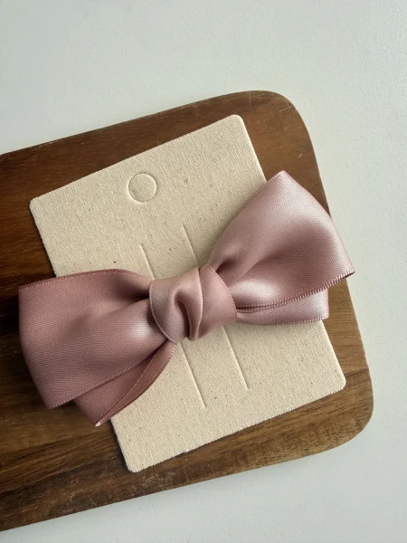 Pink satin bow for a girl on a natural, eco-friendly stand.