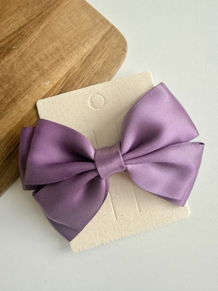 Purple satin bow for a girl on a beige base.