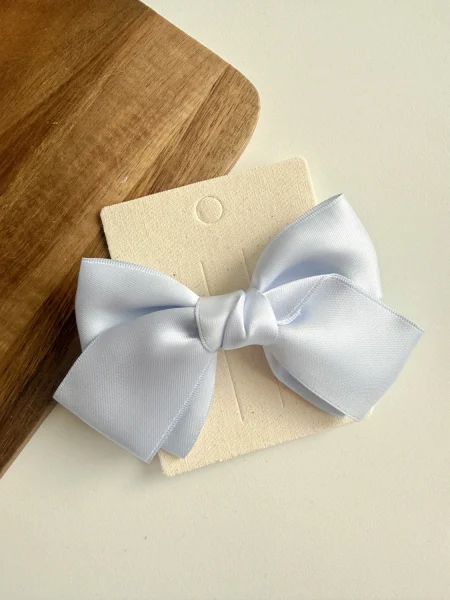 Light blue satin bow on a paper background, perfect for a girl.