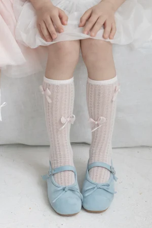 Rosa Kindersocken mit Schleifen, getragen mit blauen Schuhen. Für Mädchen.