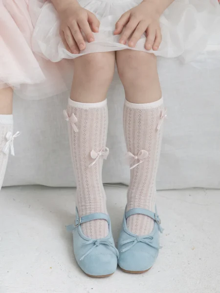 Calzini da bambina rosa con fiocchi, indossati con scarpine blu.