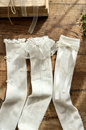 Calzini da bambina bianchi con dettagli in pizzo e fiocchi, vari modelli e lunghezze.