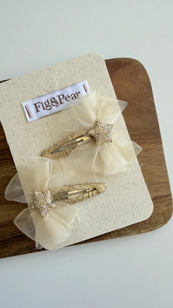 Spinki do włosów dla dziewczynki w kolorze beżowym z tiulowymi kokardkami i ozdobnymi gwiazdkami.