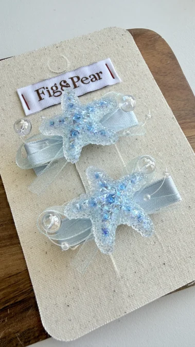 Hair clips shaped like blue glittery starfish with a satin bow.