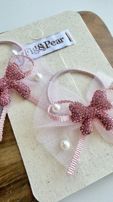 Pink bow hair ties with decorative pearls and sparkling crystals, ideal for a girl.