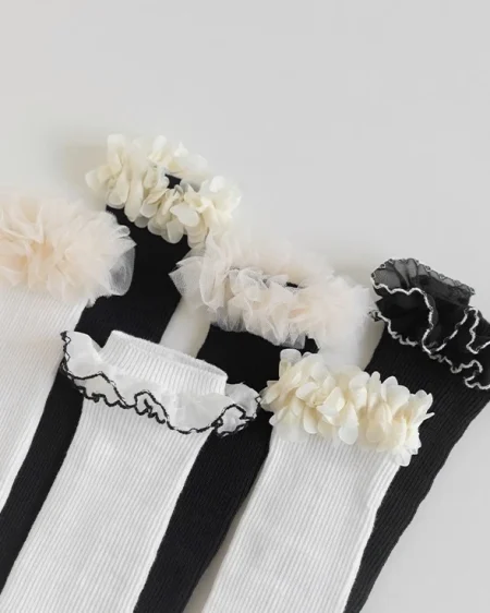 Schwarze und weiße Kniestrümpfe für Mädchen mit Rüschen und Spitzendetails.