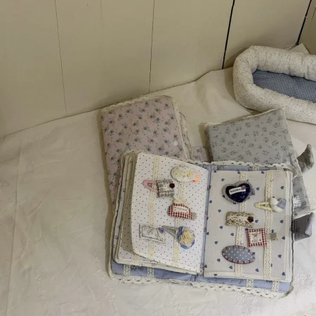 Książeczka sensoryczna w pastelowych kolorach z aplikacjami dla dziewczynki, rozwijająca umiejętności manualne.