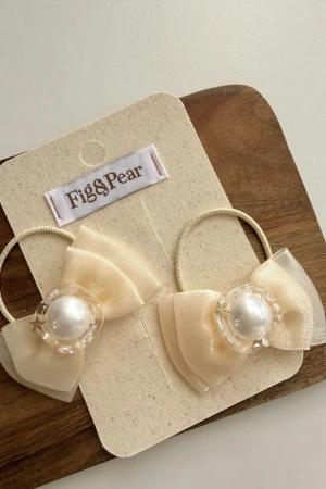 Cream hair bows with pearl embellishments, ideal for styling hair.